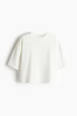 Remera blanca de corte cuadrado, con cuello redondo y mangas cortas.