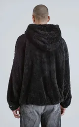 Hoodie negro oversize con cierre central al estilo anorak, confeccionado en piel de corderito sintético. Capucha ajustable con cordón y bolsillo canguro.
