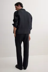 Pantalón negro de corte recto, confeccionado en mezcla de lino y algodón. Presenta cintura elástica con cordón ajustable, bolsillos laterales y bolsillo trasero insertado.