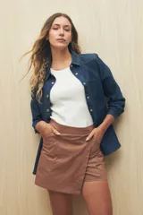 Short pollera color marrón de tiro alto, confeccionado en algodón. Presenta solapa frontal que simula una falda y bolsillos delanteros.