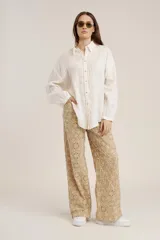 Camisa blanca de manga larga, corte holgado, con cuello camisero y detalles de bordados perforados (calado) verticales en el frente.