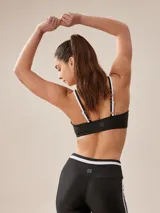Top deportivo negro con tirantes finos blancos y banda inferior blanca.
