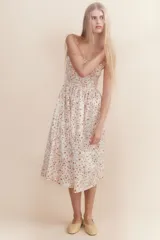Vestido midi blanco con estampado floral en tonos naranja y marrón. Tiene breteles finos, escote recto y cuerpo fruncido con elástico en el busto.