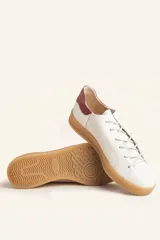 Zapatillas bajas blancas de cuero vacuno con detalle de refuerzo de gamuza color borgoña en el talón y suela de goma color caramelo.