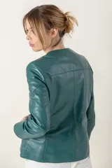 Campera azul de cuero ovino italiano, con cuello redondo, cierre frontal con broches ocultos, bolsillos laterales y detalle de capitoneado en puños y bolsillos.