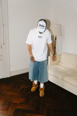 Bermuda baggy de jean celeste con lavado gastado en los laterales y bordados de letras chinas en negro y blanco.