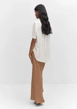 Blusa oversize de viscosa color blanco, con cuello camisero, manga corta y bolsillo frontal.