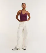 Top cropped de algodón color amarillo pálido, con escote en V pronunciado y tirantes finos que se atan en la nuca (estilo halter). El tejido es acanalado.