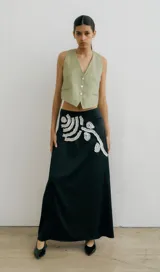 Falda larga negra con diseño de apliques blancos en la parte delantera.