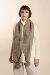 Bufanda tejida a mano en punto arroz color beige, con pompones en los extremos.