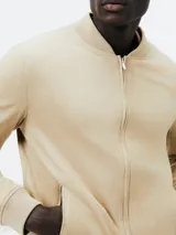 Campera tipo bomber color beige con cierre frontal, cuello, puños y ruedo acanalados.