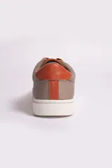 Zapatillas casuales color beige con cordones y suela de goma blanca.