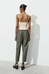 Pantalón capri color verde militar confeccionado en lino, de tiro medio, con bolsillos laterales y traseros. Cierre frontal con cremallera y botón.