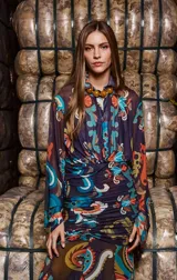 Camisa de tul elastizado con estampado paisley en tonos azul, naranja y marrón. Tiene corte clásico, cuello solapa, mangas largas acampanadas y cierre abotonado.