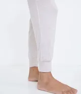 Conjunto de pijama largo en tejido de punto color gris claro. Incluye una remera de manga larga con cuello en V, botones frontales y lazo en la cintura, y un pantalón largo con cintura elástica y puños ajustados.