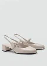 Zapato destalonado color beige con efecto charol, taco bloque de 5 cm, punta redonda y tira con hebilla.