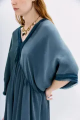 Vestido al tobillo color negro, de calce amplio y mangas al codo. Tiene apliques de gasa en escote y mangas, y recortes con frunce en la cintura.