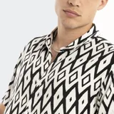 Camisa de manga corta con estampado geométrico en blanco y negro, cuello clásico y cierre frontal con botones.