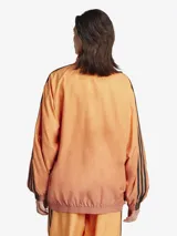 Campera deportiva Adidas Originals Firebird, color naranja con degradado, corte holgado, cierre frontal completo, cuello y puños acanalados, y las tres líneas negras características de la marca en las mangas.