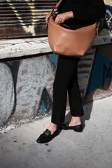 Cartera bandolera marrón de cuero, con correa regulable con hebillas, bolsillo interior y cierre metálico.