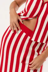 Falda larga tejida a rayas verticales rojas y blancas, con pretina elástica y tajos laterales.