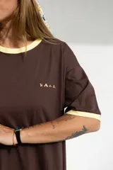 Vestido largo marrón con cuello redondo y mangas cortas con ribete amarillo. Estampado frontal con la palabra "H.A.N.D." en amarillo.