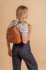 Cartera mochila color marrón de símil cuero suave con múltiples bolsillos con cierre, división al medio y correa ajustable de doble manija para llevar al hombro y como mochila.