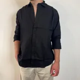 Camisa negra de lino, de corte regular, con cuello clásico y mangas largas.