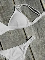 Conjunto de bikini turquesa con corpiño triangular de corte fijo, breteles regulables y almohadillas desmontables, y bombacha vedetina con frunce elástico en los costados.