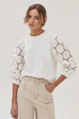 Blusa blanca de mangas 3/4 con bordado calado y cuello redondo con volados.