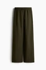 Pantalón verde militar de corte holgado en tejido liviano de mezcla de lino. Modelo de tiro alto con cintura elástica y cordón para ajustar fino, bolsillos laterales discretos y piernas rectas.