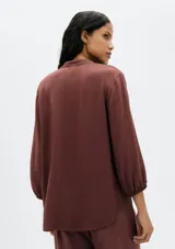 Blusa color verde claro, de mangas 3/4 con elástico en los puños, escote en V con botones y corte holgado.
