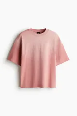 Remera rosa con efecto desteñido, corte amplio, cuello redondo y mangas cortas.