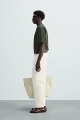 Camiseta verde oscuro de corte holgado, confeccionada en tejido de algodón grueso. Tiene cuello redondo y mangas cortas sin costura en la sisa.