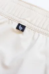 Short de baño color crema con tira lateral color borgoña y cordón de ajuste en la cintura.