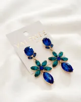Aros colgantes con forma de flor, con piedras de color azul y verde engarzadas en metal dorado.