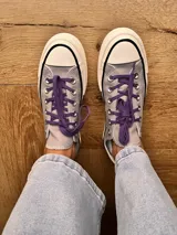 Zapatillas bajas de lona color blanco, con cordones marrones, puntera de goma y base blanca.