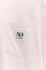 Camiseta de manga larga color rosa claro, con cuello redondo y bolsillo de parche en el pecho con logo bordado.