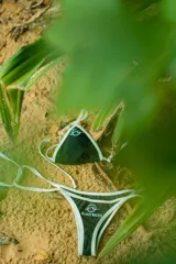 Conjunto de bikini negro con ribetes blancos. El corpiño es de corte triangular y la bombacha es tipo colaless.