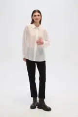 Camisa blanca traslúcida de lyocell, corte holgado, con cuello camisero, cierre frontal con botones y mangas largas con puños abotonados.