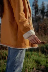 Campera gamulan color camel de cuero italiano con interior de piel sintética blanca. Tiene cuello solapa amplio, cierre con botones y bolsillos laterales.