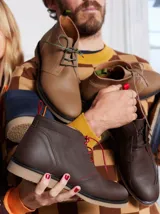 Botas acordonadas marrones de cuero, con suela de goma y costuras rojas. Incluye un par de cordones adicionales.