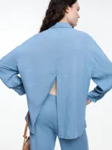 Camisa celeste de calce relajado con abertura en la espalda y mangas largas. Confeccionada en tejido liviano de lino y viscosa. Incluye tres pins decorativos.