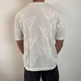 Camisa negra tejida con diseño calado, corte regular, cuello tipo polo y cierre frontal con botones.