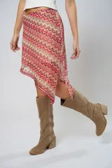 Minifalda roja con estampado de ondas en tonos rosados y beige, con corte irregular y cinturón marrón.
