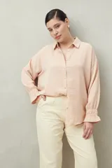 Camisa negra de manga larga con cuello clásico y botones frontales. El tejido presenta una textura arrugada o plisada, y los puños tienen un detalle fruncido o elástico.