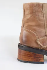 Bota corta color marrón de cuero, con hebilla metálica y taco de madera.