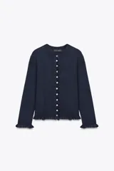 Chaqueta azul marino de punto con cuello redondo y manga larga. Presenta volantes en los bordes y cierre frontal con botones.