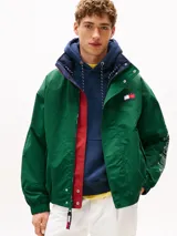 Campera náutica amplia reversible de nailon, con diseño color block en rojo, blanco y azul marino. Tiene capucha fija, cierre de cremallera oculto con botones a presión, puños y bajo elásticos, dos bolsillos ribeteados en la cintura, parche con logo de Tommy Hilfiger en el pecho y logo de Tommy Hilfiger en el cuello, las mangas y la espalda.