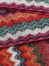 Bufanda tipo chalina con diseño de ondas en zigzag multicolor y flecos en los extremos.